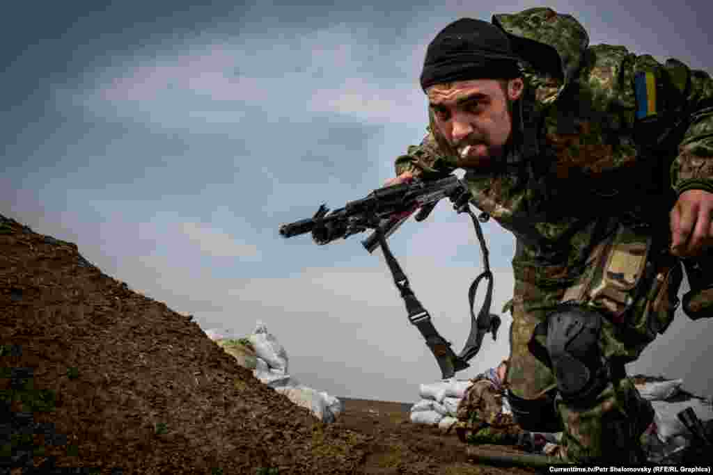 Украинский боец батальона "Азов" пытается укрыться от шквального огня противника. Посело Широкино вблизи Мариуполя. 18 апреля 2015 