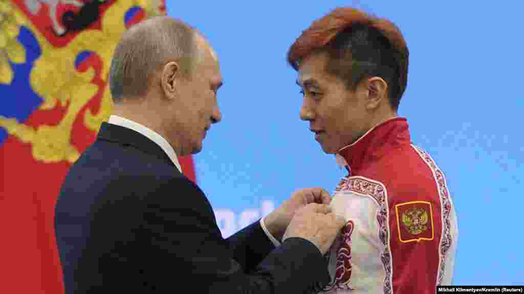 Президент России Владимир Путин на Олимпиаде в Сочи вручает награду конькобежцу Виктору Ану, который сменил гражданство с корейского на российское ради выступлений. В 2014 году Россия провела зимнюю Олимпиаду в Сочи. Она стала одной из самых дорогих в истории, так как ради нее были построены не только новые стадионы и горнолыжная инфраструктура, но также дороги, и приведен в порядок сам Сочи. Россия выиграла Олимпиаду в медальном зачете, но позже разразился допинговый скандал. Оказалось, что значительная часть российских олимпийцев принимала допинг, а программу курировали топ-чиновники Минспорта