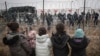Migrant children stand in front of a barbed wire fence and Polish servicemen on the Belarusian side of Poland's Kuznitsa checkpoint on November 17, 2021, as reports first surfaced of the migrants' withdrawal from the area, under Belarusian forces' supervision. 