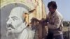 AZERBAIJAN -- A Baku resident cuts out with an axe 21 September 1991 in Baku a placard showing a portrait of Russain Bolshevik revolutionary leader Vladimir Ilyich Lenin.