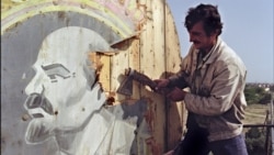AZERBAIJAN -- A Baku resident cuts out with an axe 21 September 1991 in Baku a placard showing a portrait of Russain Bolshevik revolutionary leader Vladimir Ilyich Lenin.