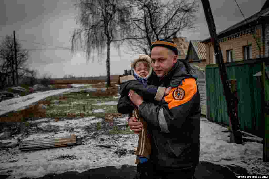 Спасатель МЧС выносит ребенка из дома 
