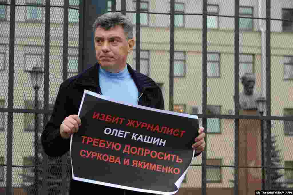 Борис Немцов держит плакат с требованием начать расследование по делу избиения оппозиционного журналиста Олега Кашина 