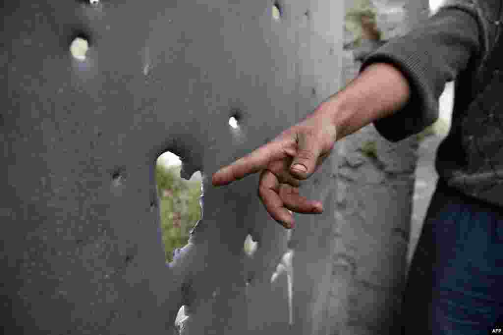 A resident of the Azerbaijani town of Tartar, north of Nagorno-Karabakh, shows apparent shell damage to another gate. 
