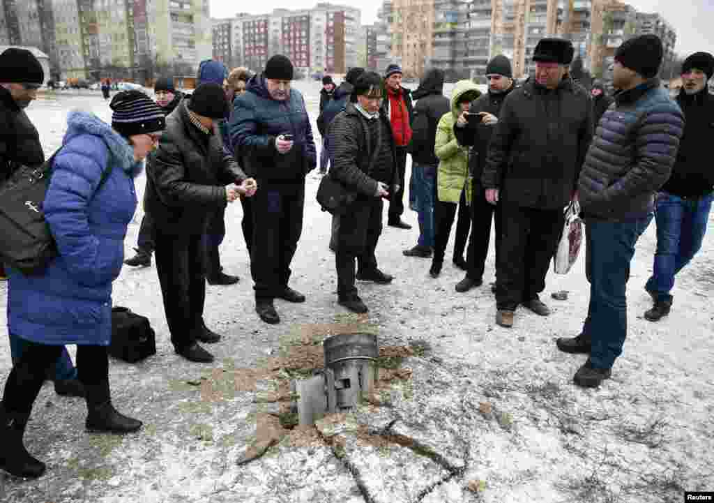 Люди осматривают реактивный снаряд, упавший на одной из улиц Краматорска 
