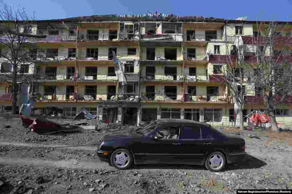 Before the arrival of Azerbaijani troops, a man drives a car past a building reportedly damaged from shelling of the Karabakhi town of Shushi (Shusha) in late October 2020. Badly damaged buildings from the first Karabakh war in the early 1990s can still be found throughout the town.