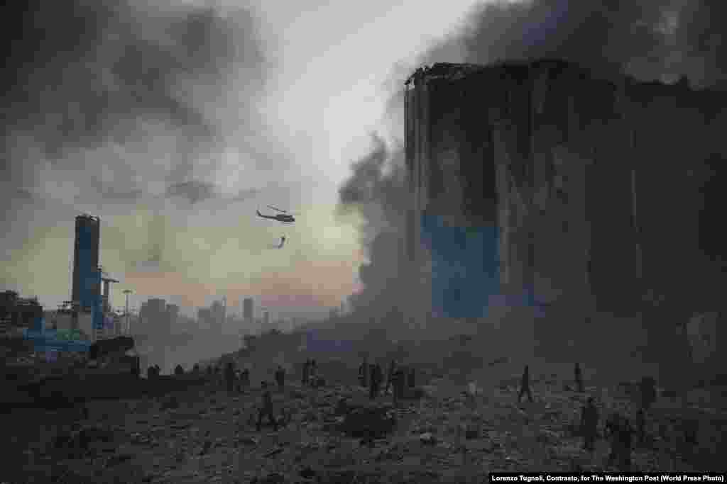 Снимок из фоторепортаж "Взрыв в порту Бейрута". На месте катастрофы работают пожарные (4 августа 2020). Около десяти пожарных погибли на месте взрыва. Первое место в категории "Срочные новости, фоторепортаж", автор – Лоренсо Тугноли