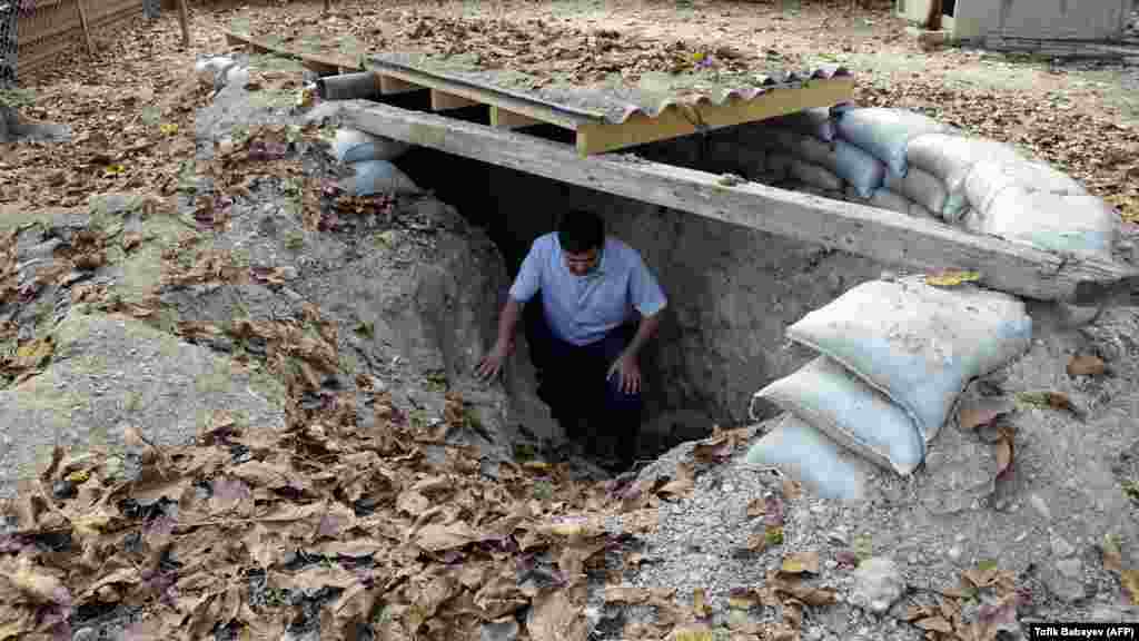 A resident of the Azerbaijani town of Tartar shows a self-made bomb shelter in the courtyard of his house.