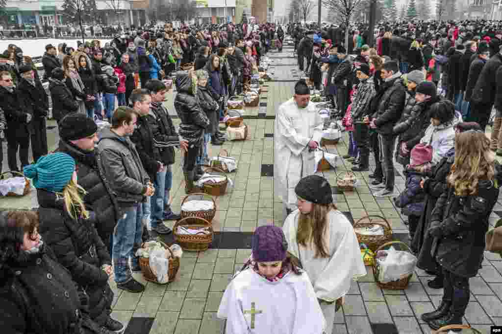 На фото – румынский католический священник благославляет корзины с едой на главной площади города Меркуря-Чук