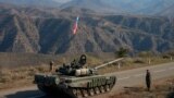 Servicemen from Russian peacekeeping troops stand next to a tank near the Armenian border following the signature of a November 9, 2020 deal to end the military conflict between Azerbaijan and ethnic Armenian forces in the breakaway region of Nagorno-Karabakh. 