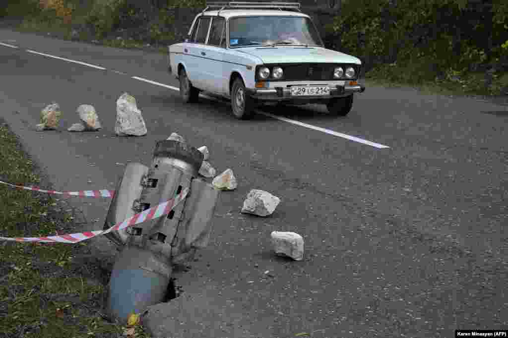 A car drives past the remains of a rocket shell near Shushi (Shusha) in late October 2020. Until 2017, the twisty, two-lane mountain road running from Karabakh's main town, Stepanakert, through Shushi was the only way for local residents to reach Armenia. 