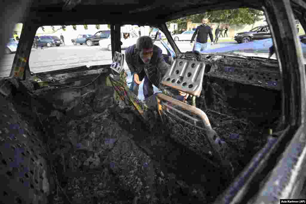 AZERBAIJAN -- A man looks in a burnt out car after multiple rocket system shelling by Armenian forces in Barda, Azerbaijan, Wednesday, Oct. 28, 2020.