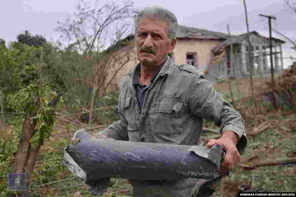 A man at an undisclosed location holds part of an artillery shell, fired during renewed fighting in September 2020 between Armenian, Karabakhi, and Azerbaijani forces over the Nagorno-Karabakh region. The photo was published by the Armenian Foreign Ministry. 