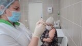 A nurse at Russia's Kemerovo Clinical Diagnostic Center prepares to vaccinate fellow nurse Olga Skripachenko with the Sputnik-V vaccine on December 9, 2020.